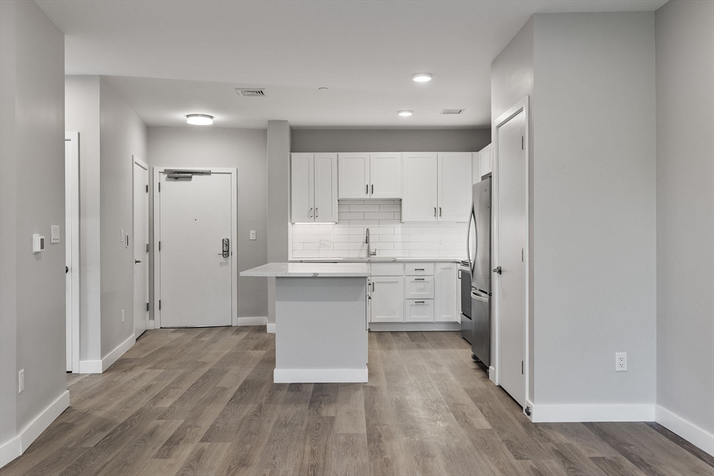59 Mill Street, Unit 111 Woburn, MA 01801 - Photo 4 of 18 a kitchen with white cabinets and stainless steel appliances