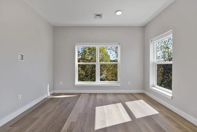 an empty room with wooden floor and windows