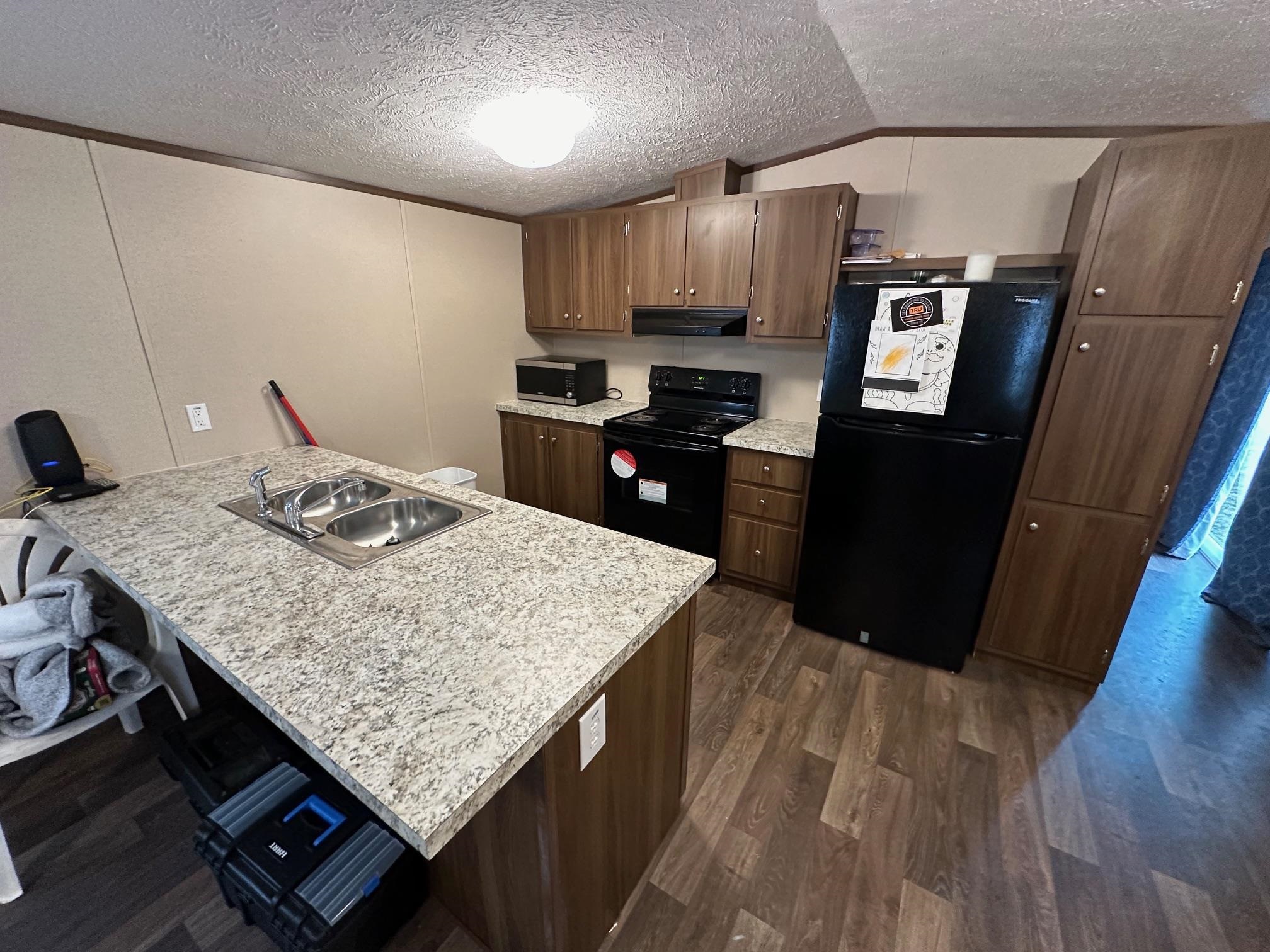 1696 Hardin Graveyard Road Adamsville, TN 38310 - Photo 12 of 25 a kitchen with granite countertop wooden cabinets a refrigerator and microwave