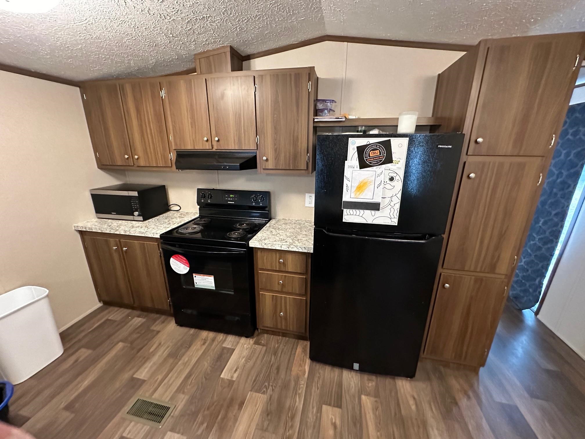 1696 Hardin Graveyard Road Adamsville, TN 38310 - Photo 13 of 25 a kitchen with granite countertop a refrigerator a sink and wooden cabinets