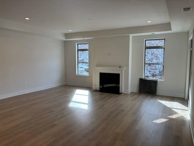 an empty room with wooden floor fireplace and windows