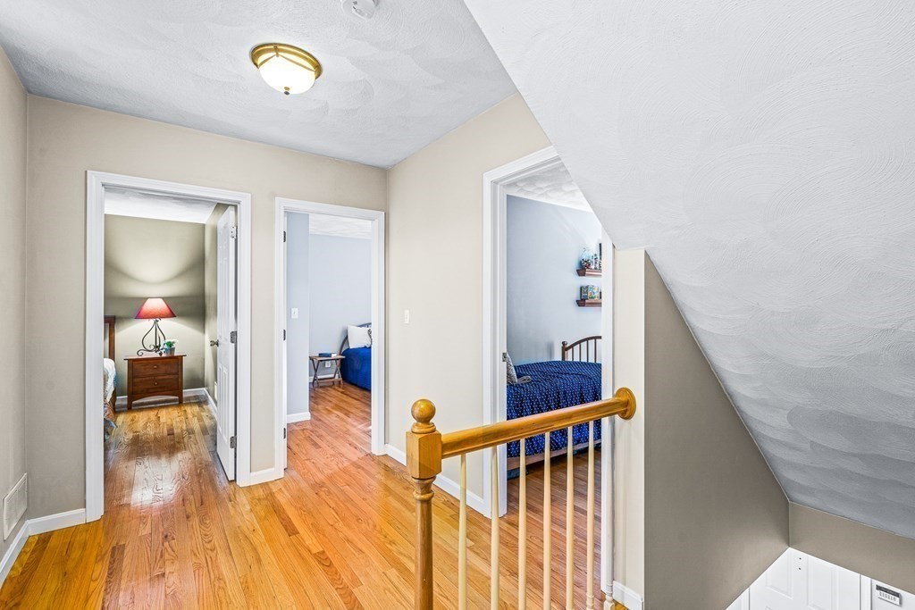 18 Ravens Bluff Andover, MA 01810 - Photo 19 of 41 a view of a hallway to a livingroom with wooden floor and stairs