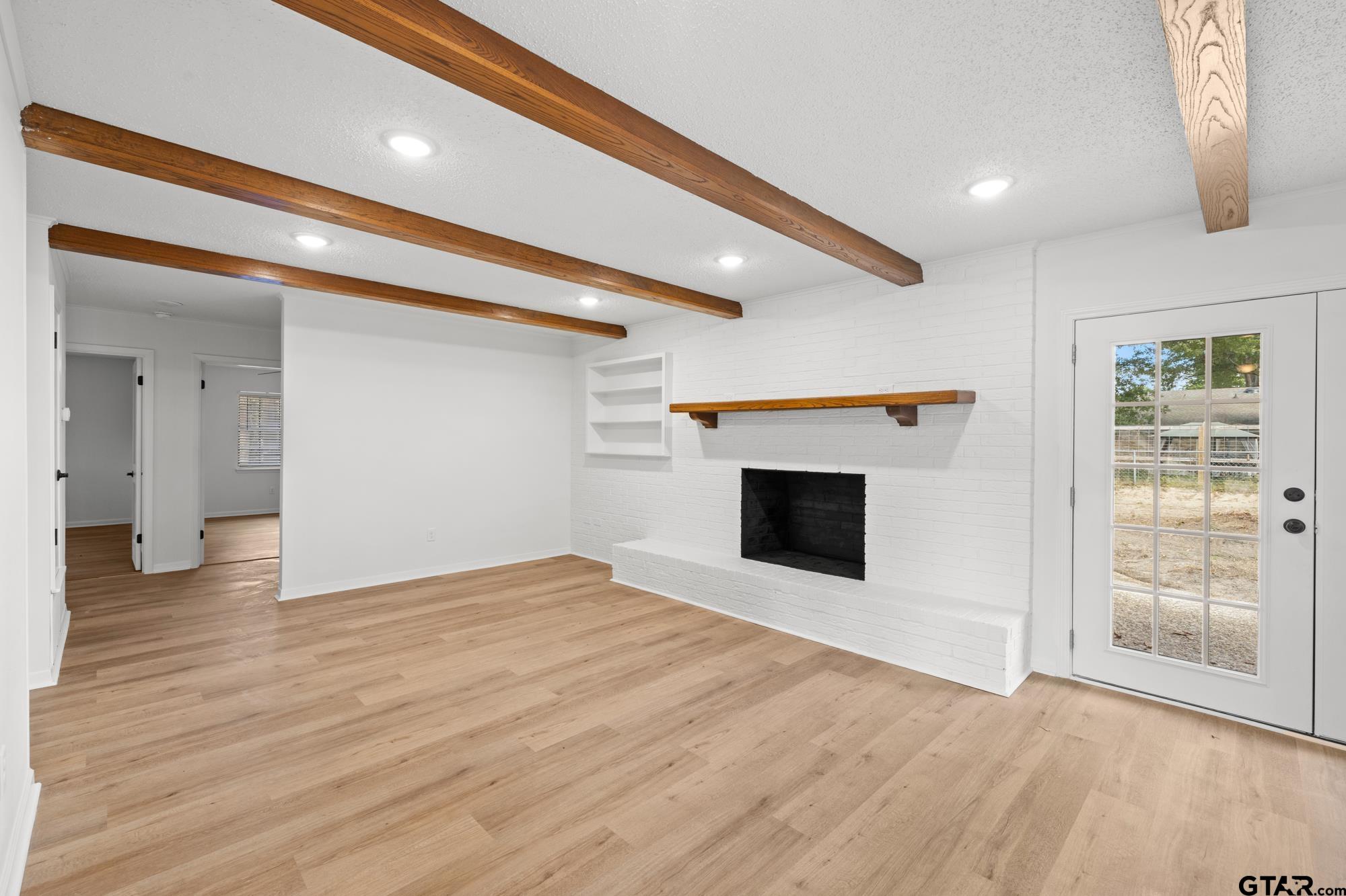 810 Pineland Lane Lindale, TX 75771 - Photo 12 of 42 a view of an empty room with wooden floor and a fireplace