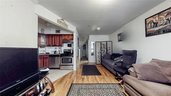 a living room with stainless steel appliances furniture a rug and a kitchen view