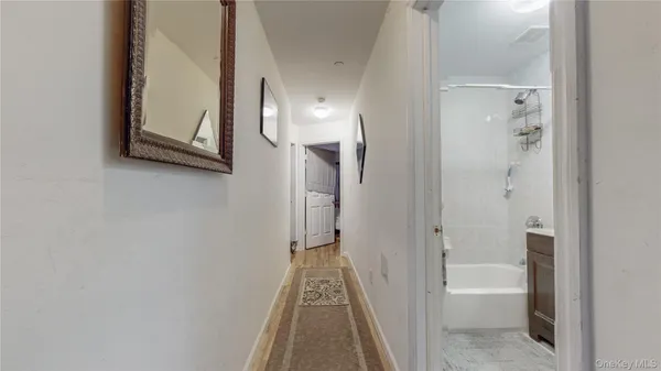 a view of a hallway with wooden floor and a bathroom