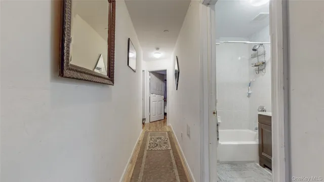 a view of a hallway with wooden floor and a bathroom