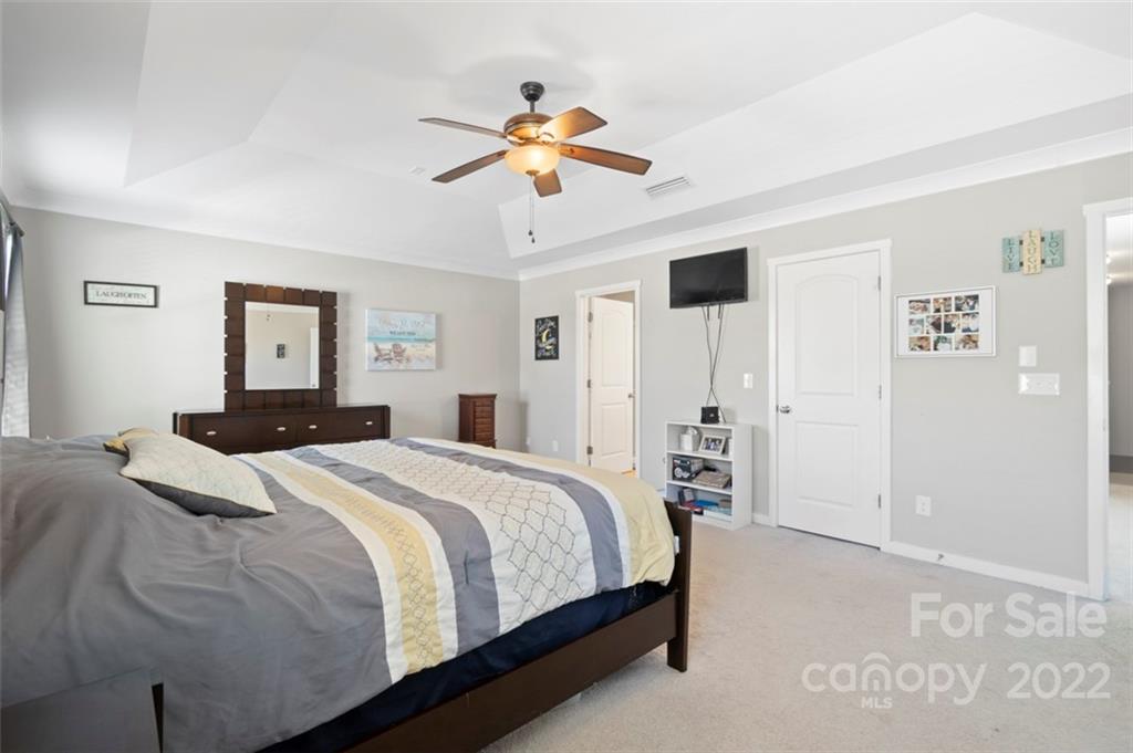 8218 Midas Lane Locust, NC 28097 - Photo 14 of 34 a bedroom with a large bed and a chandelier