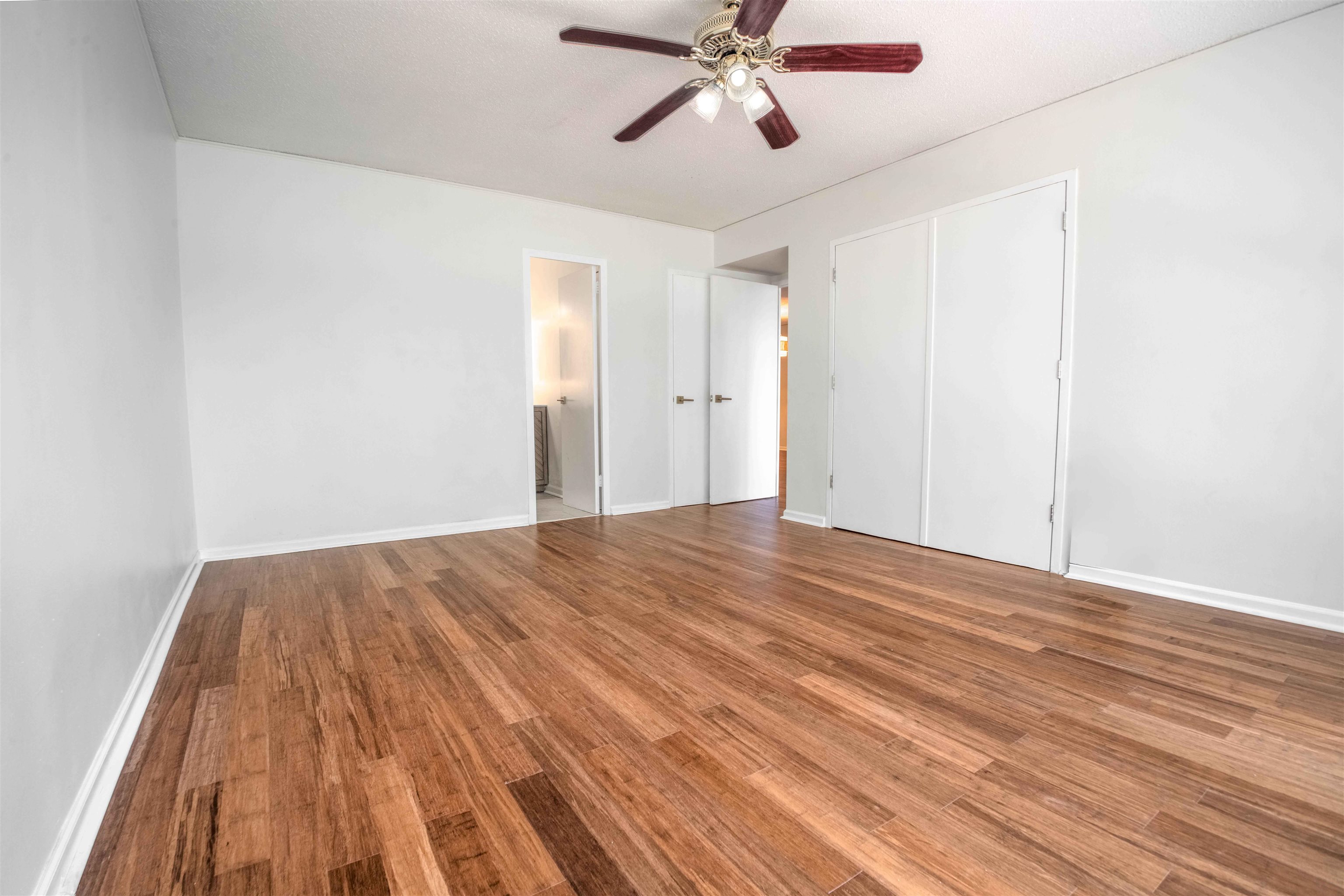 3080 Walnut Grove Road, Unit 306 Memphis, TN 38111 - Photo 13 of 18 Room featuring wood-finish flooring, white walls, and a ceiling fan with light fixture
