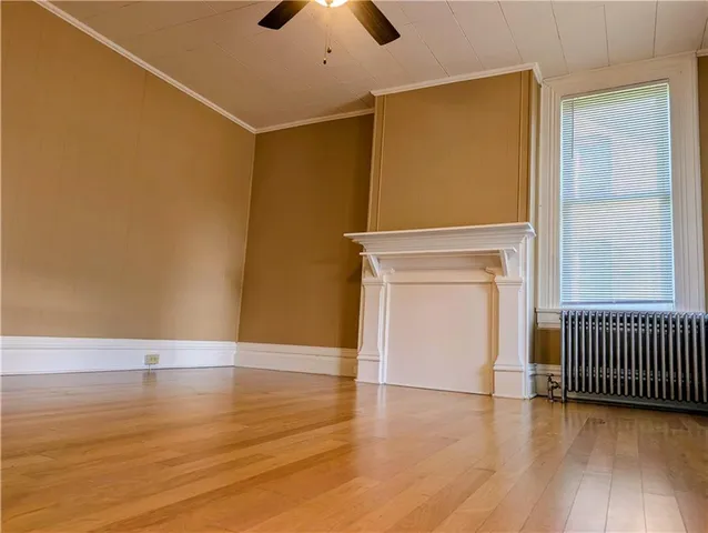 an empty room with wooden floor chandelier fan and windows