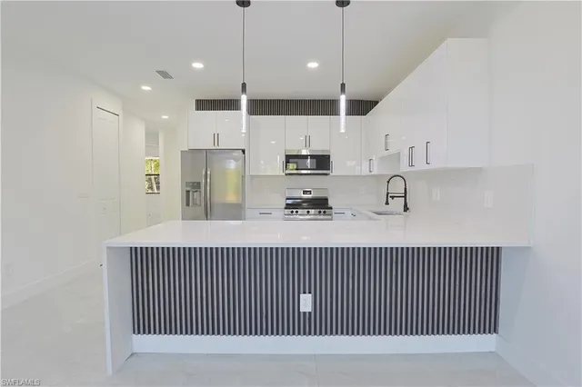 a kitchen with kitchen island stainless steel appliances sink cabinets and window