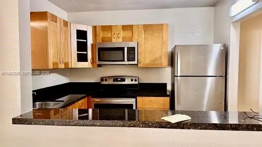 a kitchen with stainless steel appliances granite countertop a stove a microwave and a refrigerator