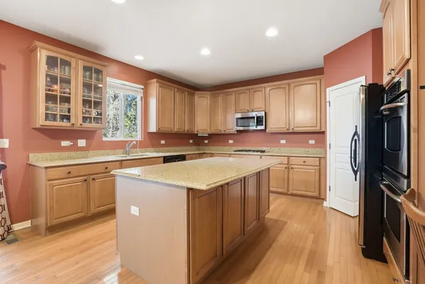 a kitchen with stainless steel appliances granite countertop a refrigerator a sink dishwasher a stove with wooden cabinets and floor