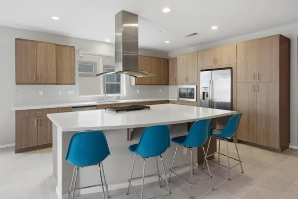 a kitchen with stainless steel appliances granite countertop a sink a stove a refrigerator and chairs with wooden floor