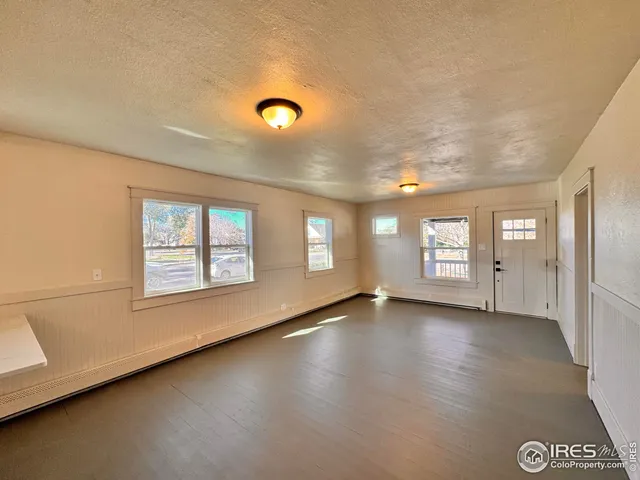 a view of an empty room with a window and wooden floor