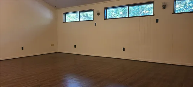 a view of an empty room with wooden floor and windows