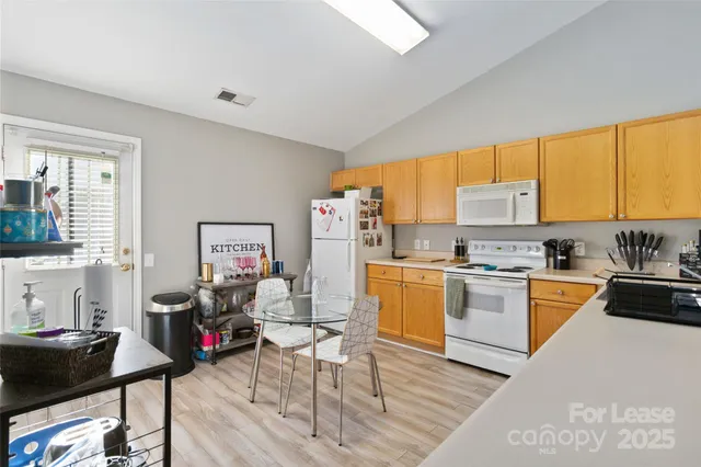 a kitchen with stainless steel appliances granite countertop a stove top oven a sink dishwasher and white cabinets with wooden floor