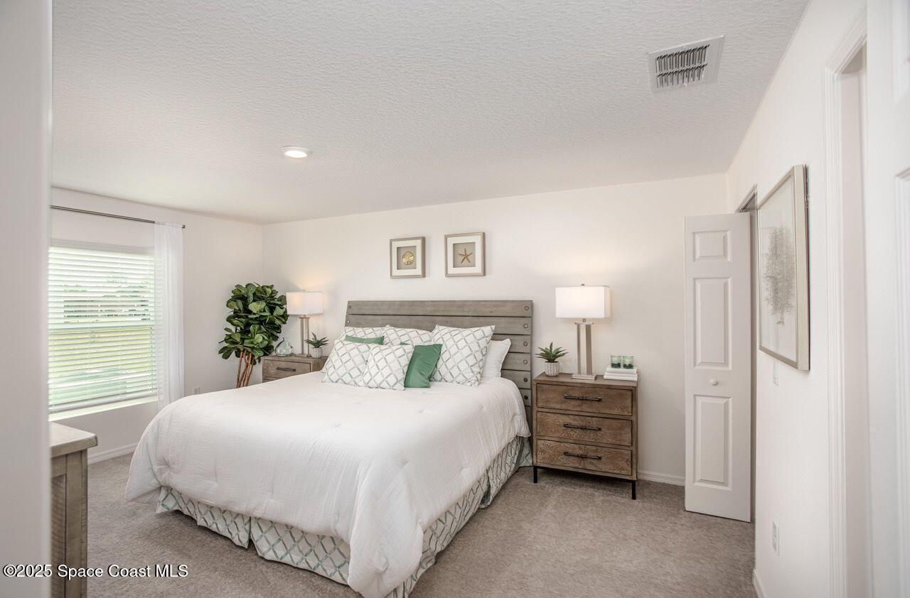592 Plumbago Road Northwest Palm Bay, FL 32907 - Photo 11 of 20 a bedroom with a bed a lamp and a window