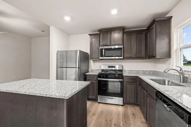 a kitchen with stainless steel appliances granite countertop a sink stove microwave and refrigerator