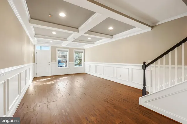 a view of an empty room with wooden floor and stairs