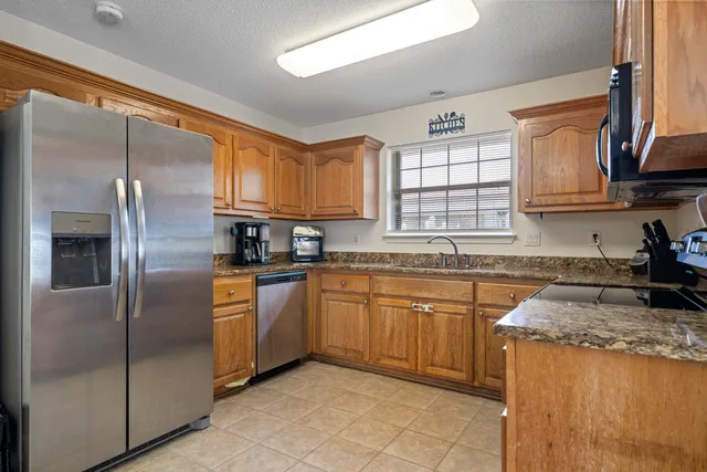 a kitchen with granite countertop stainless steel appliances a sink window and cabinets
