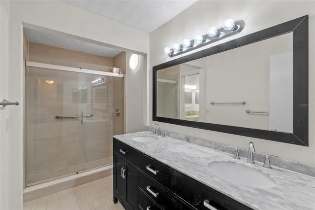 a bathroom with a granite countertop sink a large mirror and shower