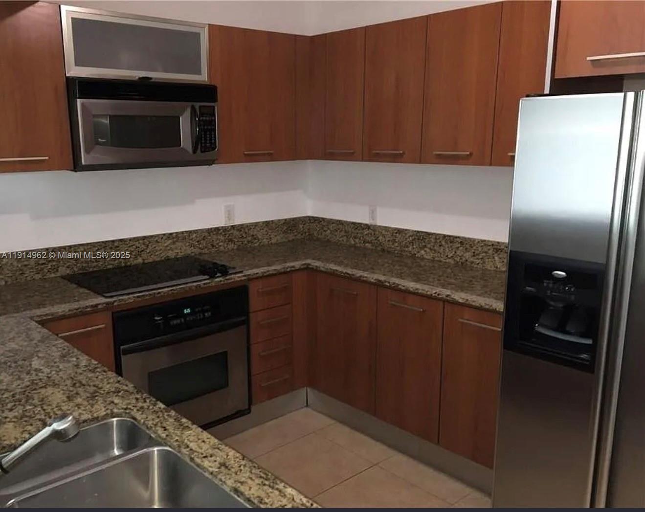 9066 Southwest 73rd Court, Unit 2101 Miami, FL 33156 - Photo 3 of 10 a kitchen with granite countertop stainless steel appliances and wooden cabinets