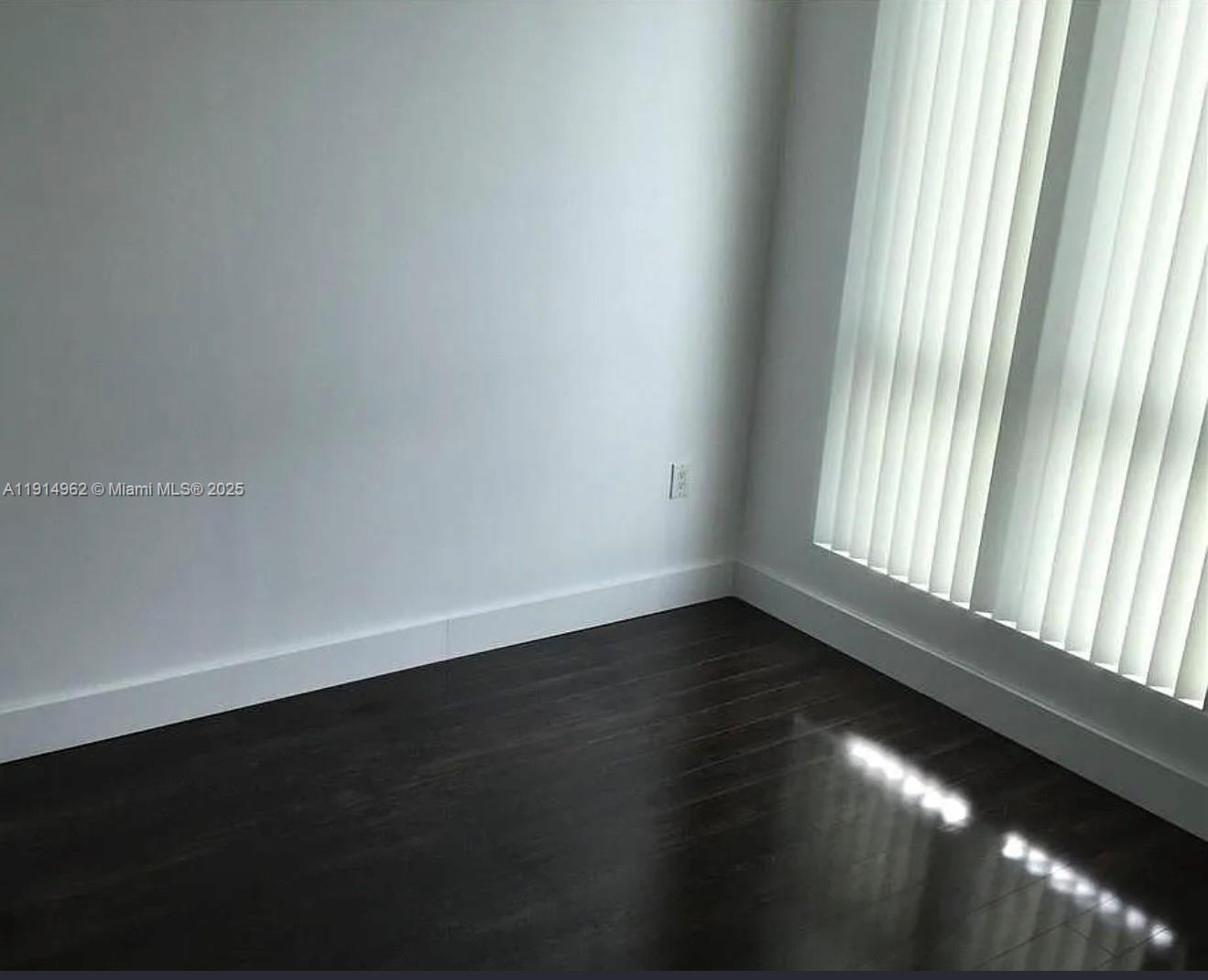 9066 Southwest 73rd Court, Unit 2101 Miami, FL 33156 - Photo 5 of 10 a view of an empty room with wooden floor and a window