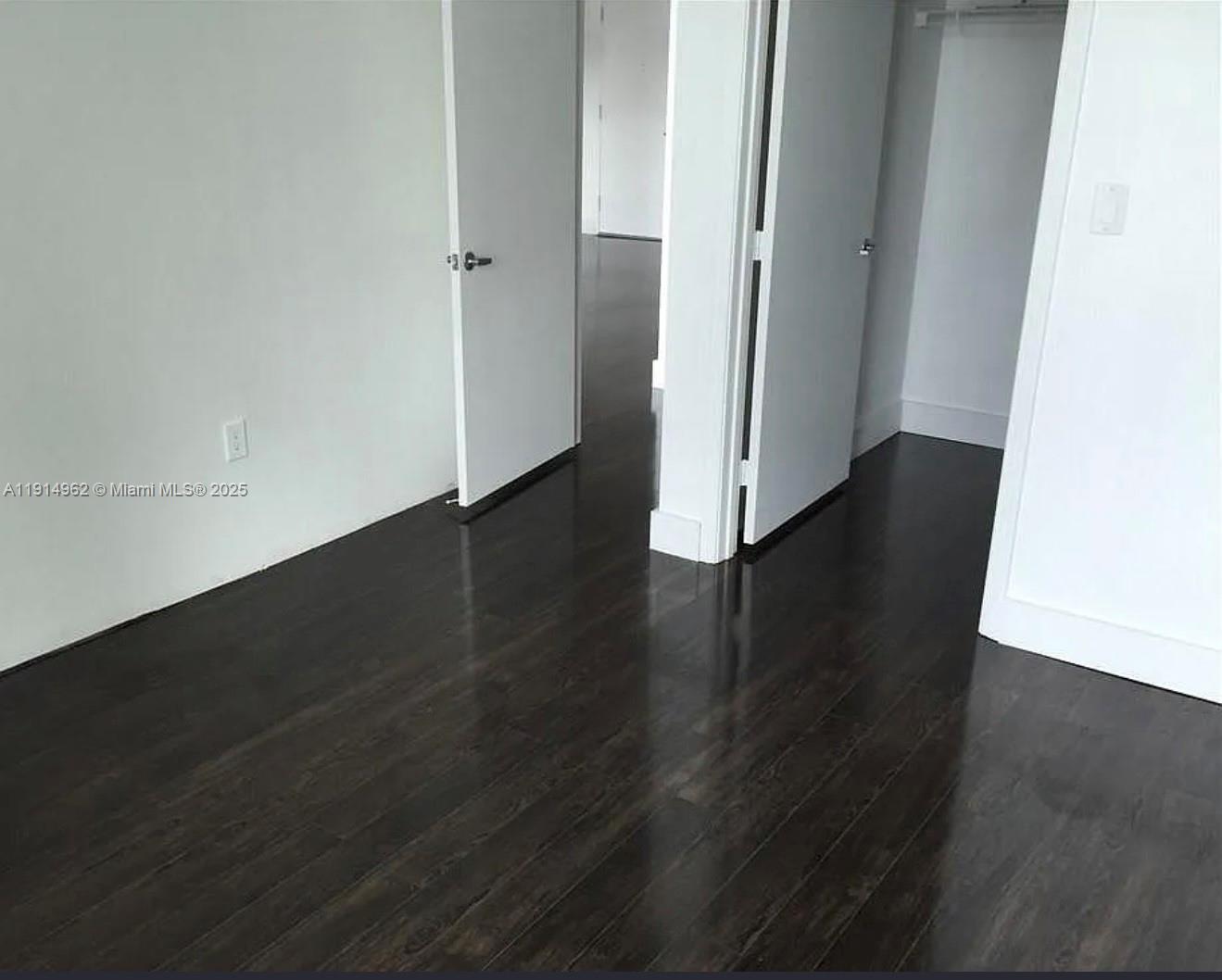 9066 Southwest 73rd Court, Unit 2101 Miami, FL 33156 - Photo 7 of 10 an empty room with wooden floor and closet