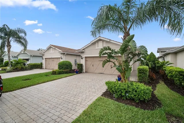 a front view of a house with a garden and palm trees