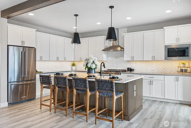 a kitchen with kitchen island granite countertop a sink a stove a refrigerator and island with wooden floor