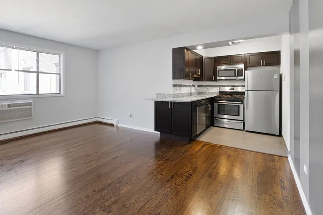a kitchen with kitchen island wooden floors appliances and window