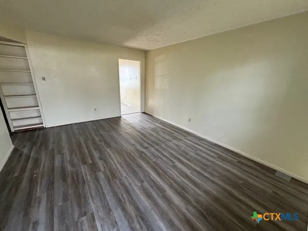 a view of an empty room with wooden floor