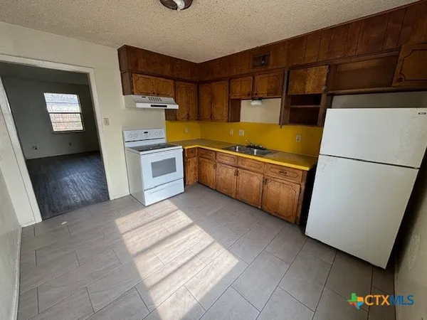 a kitchen with granite countertop a refrigerator and a stove top oven