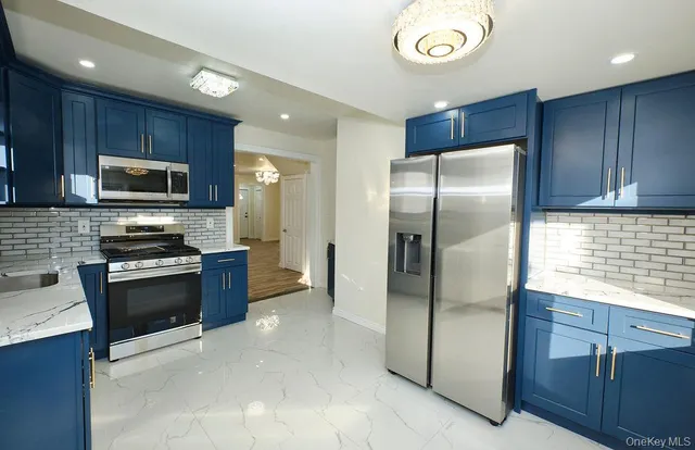 a kitchen with stainless steel appliances granite countertop a refrigerator a stove a sink and a microwave