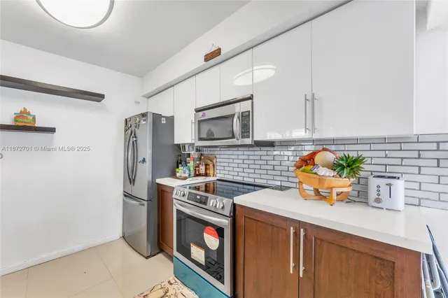 a kitchen with stainless steel appliances a stove a refrigerator a sink a counter space and wooden floor