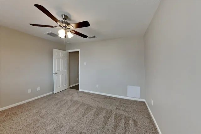 an empty room with windows and ceiling fan
