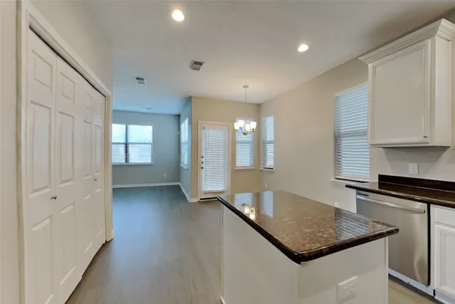 a kitchen with stainless steel appliances granite countertop a sink a stove and white cabinets