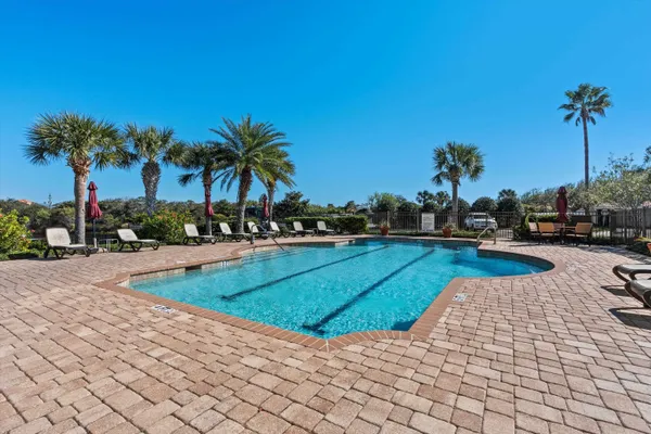 a view of a swimming pool with a yard and palm trees