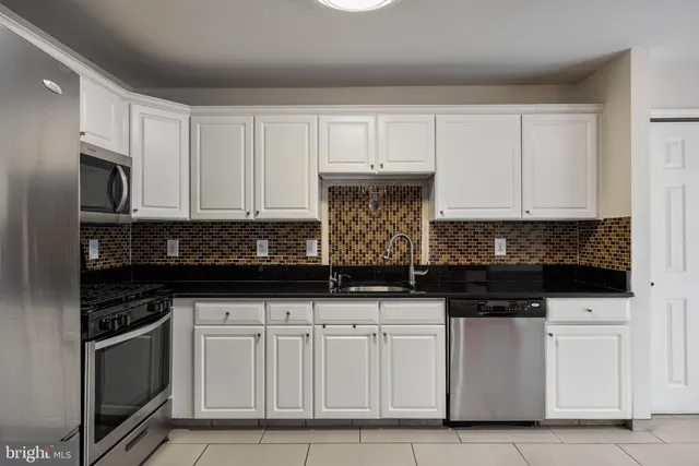 a kitchen with white cabinets and appliances