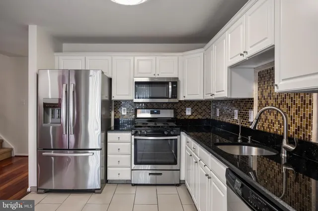 a kitchen with granite countertop a refrigerator stove and sink