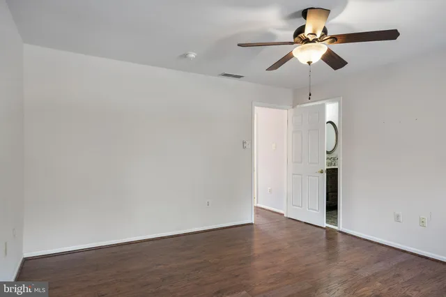 an empty room with wooden floor closet and fan