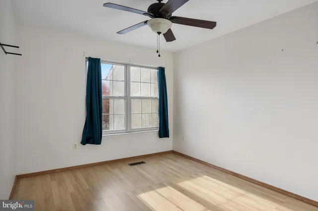 an empty room with wooden floor chandelier fan and windows