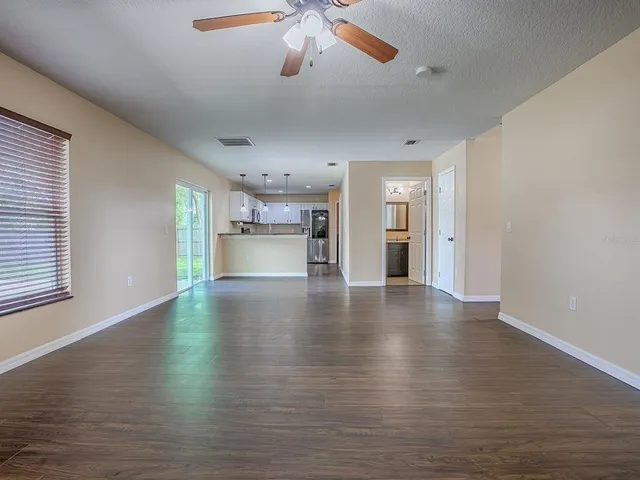a view of an empty room with wooden floor and window