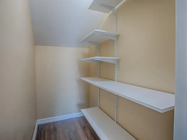 an empty room with wooden floor closet and windows