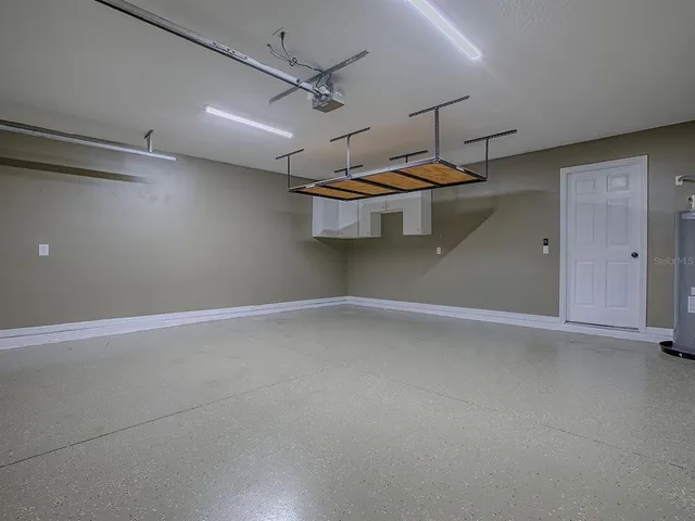 an empty room with wooden floor chandelier fan and windows