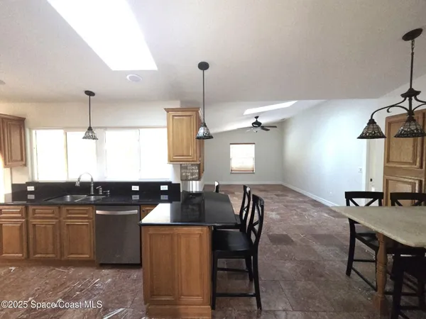a kitchen with granite countertop a sink a counter space dining table and chairs