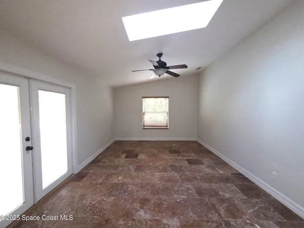 an empty room with a window and a ceiling fan