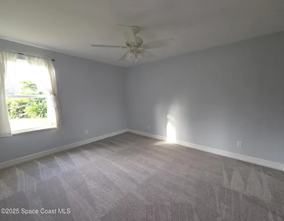an empty room with a window and a fan