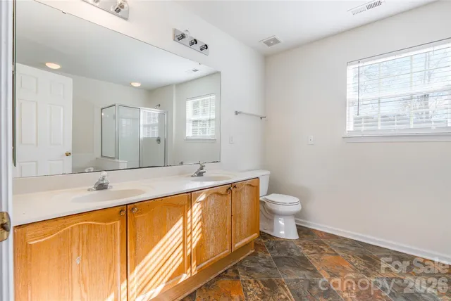 a bathroom with a granite countertop sink toilet and mirror