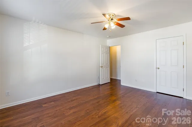 an empty room with wooden floor and a ceiling fan